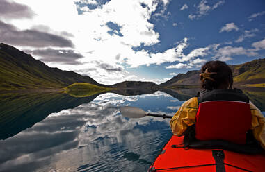 Woman rowing sea kayak on still lake in central Iceland - CAVF85725