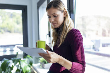 Geschäftsfrau mit Kaffeebecher und digitalem Tablet im Büro - JSRF00966