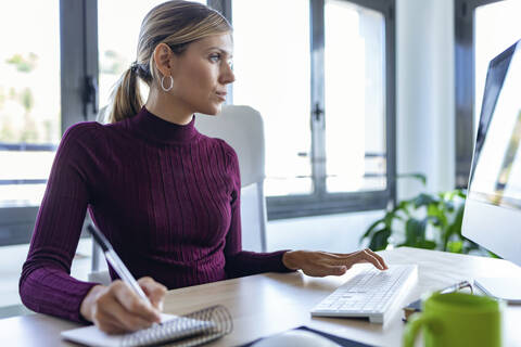 Businesswoman using computer on desk while sitting in office stock photo