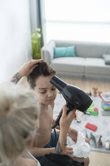 Friseurin trocknet die Haare eines hemdlosen Jungen zu Hause - SNF00373