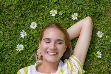 Close-up of smiling woman with eyes closed lying on grassy land in park - LBF03083