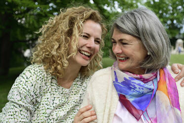 Cheerful blond woman looking at senior woman in park - ECPF00958