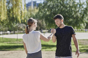 Frau begrüßt Trainer vor dem Training im Park - JNDF00172