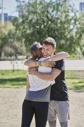 Embracing couple before work out in park - JNDF00174