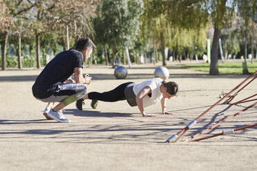 Frau beim Workout mit Trainer im Park - JNDF00177