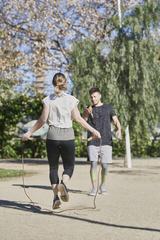 Frau beim Training mit Trainer, der im Park Seil springt, lizenzfreies Stockfoto