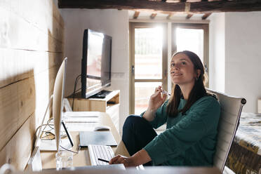 Female architect using computer and looking up at home - JRFF04519