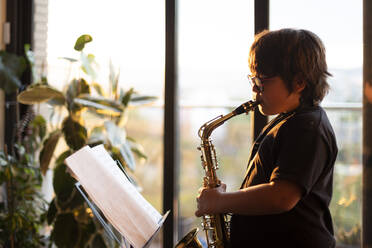 Junge übt abends zu Hause das Saxophonspielen - VABF03086