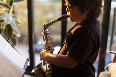 Junge übt abends zu Hause das Saxophonspielen - VABF03087