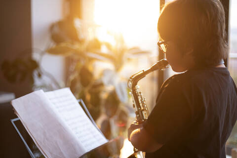 Junge übt abends zu Hause das Saxophonspielen, lizenzfreies Stockfoto