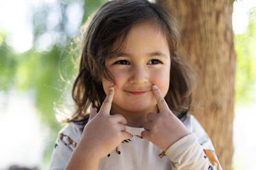 Portrait of smiling little girl with fingers on her face - VABF03096