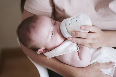 Mother bottle feeding baby girl at home - EBBF00192