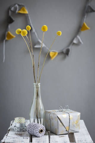Wrapped gift and bottle with blooming billy buttons stock photo