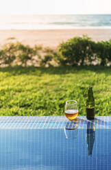 Open beer left at edge of outdoor swimming pool in summer - EHF00369