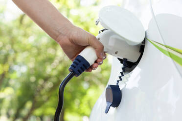 Cropped Hand Of Woman Charging Electric Car At Station - EYF07290