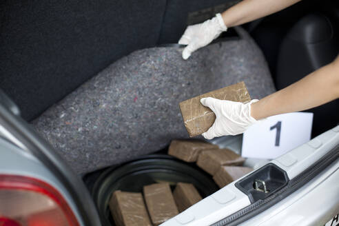 Beschnittenes Bild des Ermittlers auf der Suche nach einer geschmuggelten Droge im Kofferraum eines Autos - EYF07323