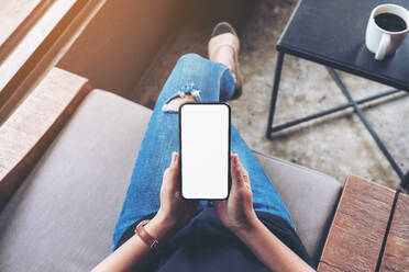 Low Section Of Woman Using Mobile Phone While Sitting On Sofa At Home - EYF07410