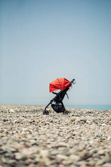 Georgia, Adjara, Batumi, Baby stroller left on rocky coastal beach in summer - WVF01802