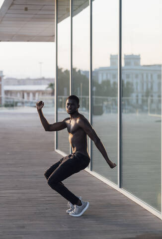 Junger Mann ohne Hemd tanzt am Fensterglas, lizenzfreies Stockfoto