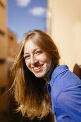 Porträt einer glücklichen jungen Frau mit Nasenpiercing auf dem Balkon - TCEF00782