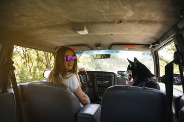 Lächelnde Frau fährt Auto und sitzt mit Husky - JCMF00890