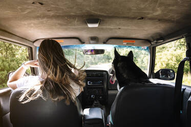 Frau mit langen blonden Haaren fährt mit Husky auf Road Trip - JCMF00892