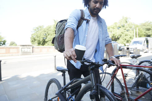 Junger Mann parkt Fahrrad vor dem Bahnhof - PMF01102