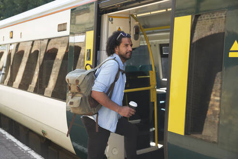 Young trendy man boarding train at railroad station - PMF01107