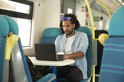 Young trendy man using laptop in train stock photo
