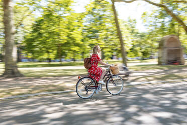 Unscharfe Bewegung einer Frau beim Fahrradfahren auf dem Fußweg im Park - WPEF03065