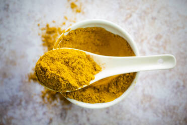 Bowl and spoon of yellow curry powder - GIOF08476