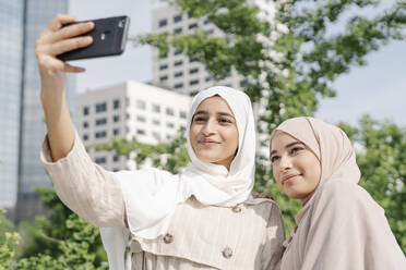 Muslimische Schwestern machen Selfie mit Smartphone in der Stadt - JCZF00144