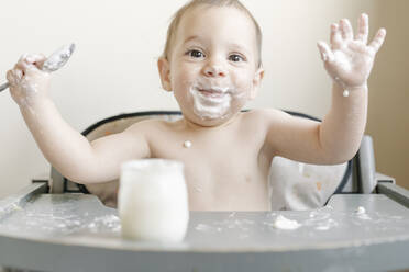 Little baby boy eating yogurt in highchair at home - JCZF00165