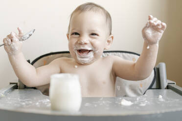 Little baby boy eating yogurt in highchair at home - JCZF00166