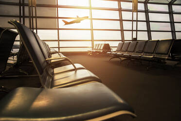 Flugzeug fliegt gegen den Himmel von leeren Flughafen Abflugbereich Fenster gesehen - EYF07483