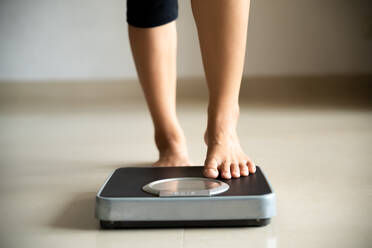 Low Section Of Woman Standing On Weight Scale At Home - EYF07528