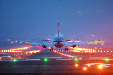 Flugzeug fliegt über Landebahn gegen Himmel bei Nacht - EYF07538