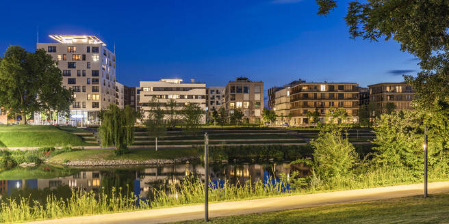 Deutschland, Baden-Württemberg, Heilbronn, Neckar, Stadtteil Neckarbogen, Neue energieeffiziente Wohngebäude bei Nacht beleuchtet - WDF06079