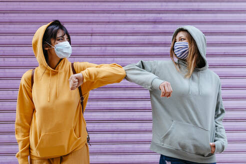 Young woman wearing masks greeting with elbow - TCEF00791