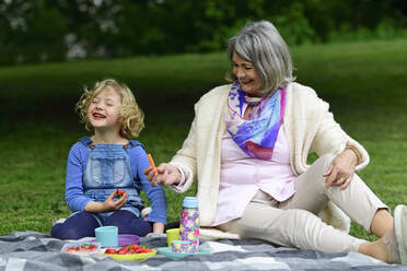 Cheerful grandmother and granddaughter having picnic at park - ECPF00961