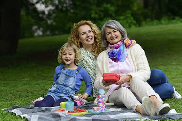 Fröhliche Frauen der dritten Generation genießen ein Picknick im öffentlichen Park - ECPF00964