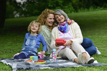 Glückliche Frauen der dritten Generation genießen ein Picknick im öffentlichen Park - ECPF00965