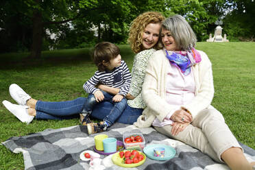 Glücklicher Junge genießt Picknick mit Mutter und Großmutter im öffentlichen Park - ECPF00969