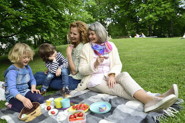 Glückliche Familie in der dritten Generation beim Picknick im öffentlichen Park - ECPF00973