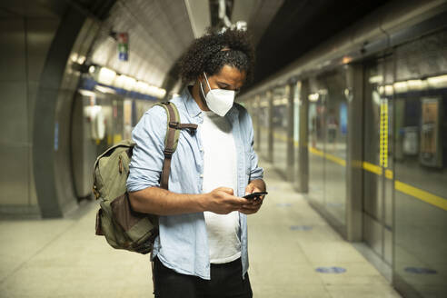 Junger Mann mit Schutzmaske auf dem Bahnsteig einer U-Bahn-Station, London, UK - PMF01115