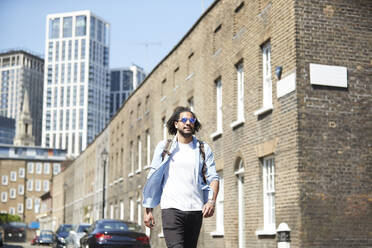 Porträt eines jungen Mannes mit Rucksack auf einer Wohnstraße, London, UK - PMF01121