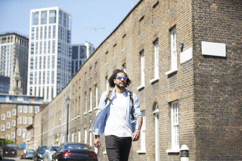 Porträt eines jungen Mannes mit Rucksack auf einer Wohnstraße, London, UK - PMF01121