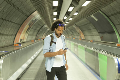 Porträt eines jungen Mannes, der auf sein Mobiltelefon schaut, London, UK, lizenzfreies Stockfoto