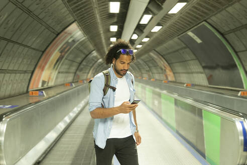 Porträt eines jungen Mannes, der auf sein Mobiltelefon schaut, London, UK - PMF01125