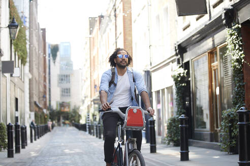 Porträt eines jungen Mannes auf einem Mietfahrrad in der Stadt, London, UK - PMF01145